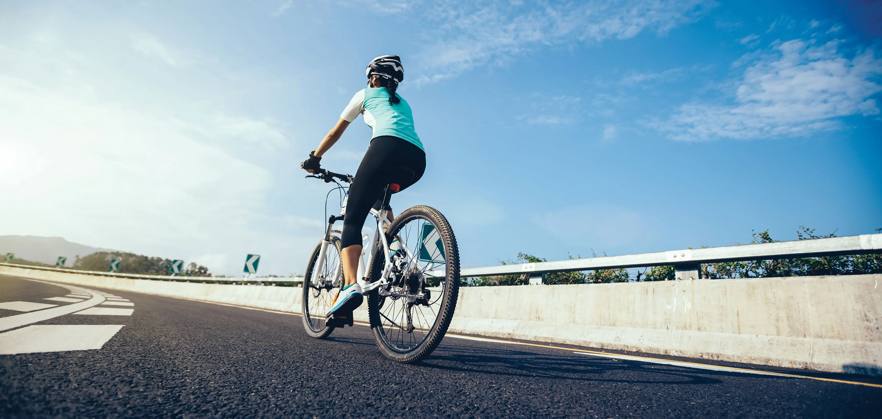 back view of woman cycling under blue sky