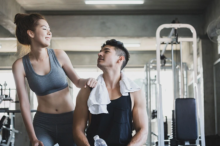 sporty man and woman smiling at each other in gym