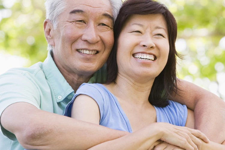 middle age man smiling and hugging wife from behind