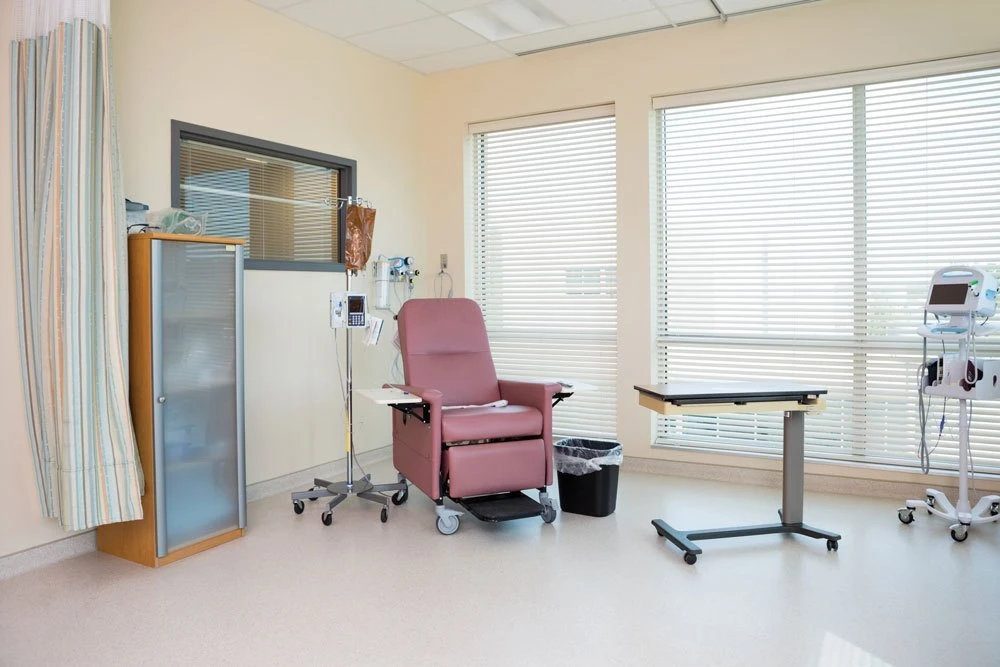 chemotherapy room with pink treatment seat and wooden cabinet on the left