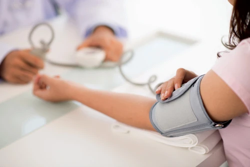 woman measuring blood pressure on left arm with machine