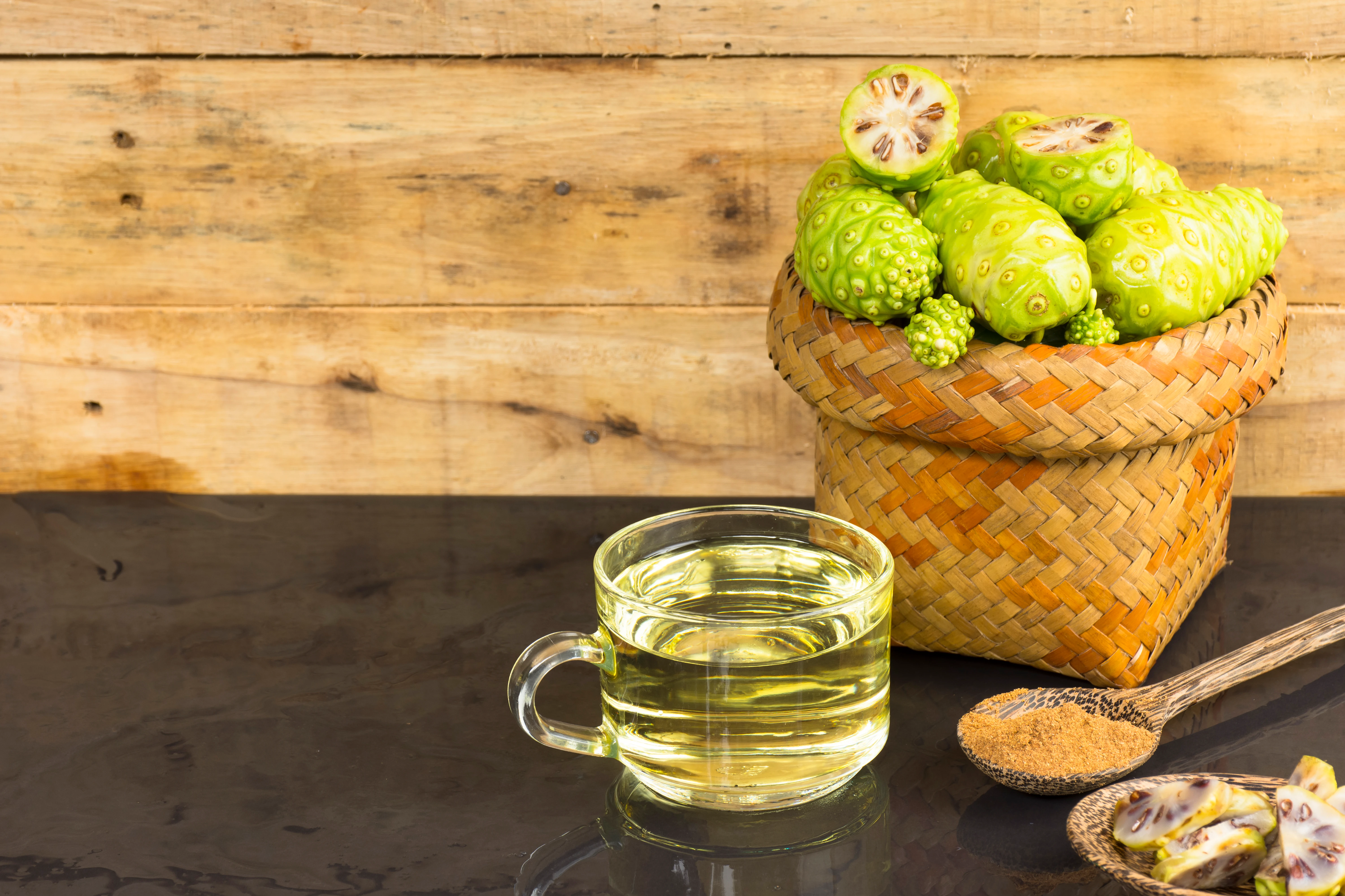 noni fruit and noni juice with noni powder on black table